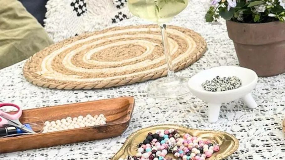 Beads, scissors, and wine on a lace tablecloth.