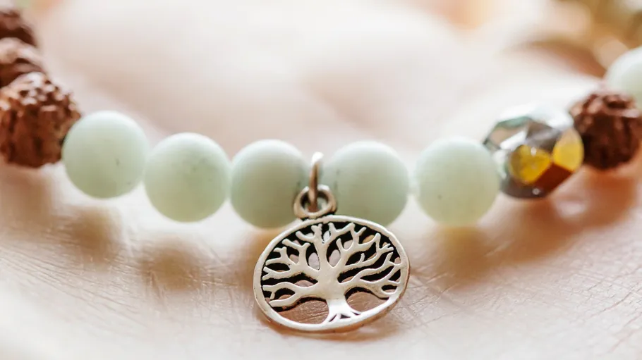 Armband mit Baumanhänger auf einer Hand.