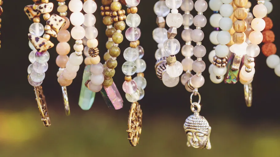 Colorful beaded necklaces with charms hanging outdoors.