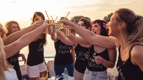 Women celebrate on a boat with drinks.