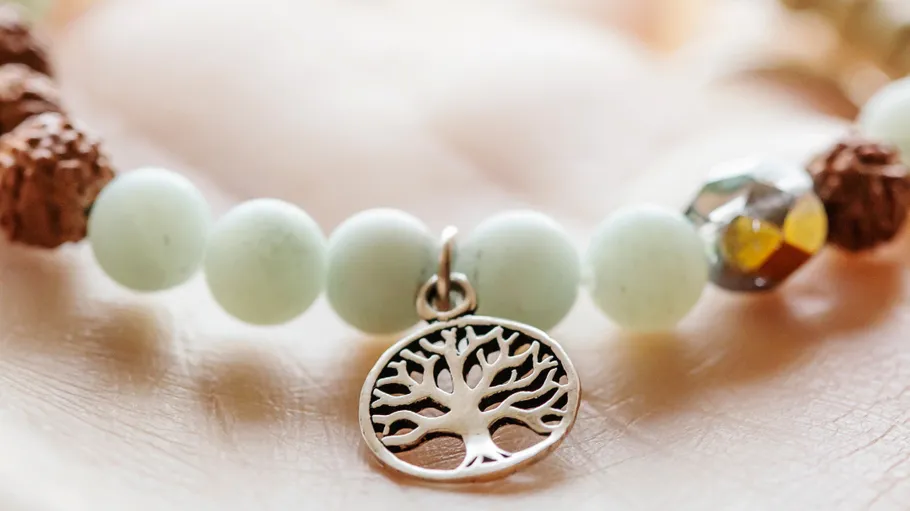 Bracelet with tree charm on hand.