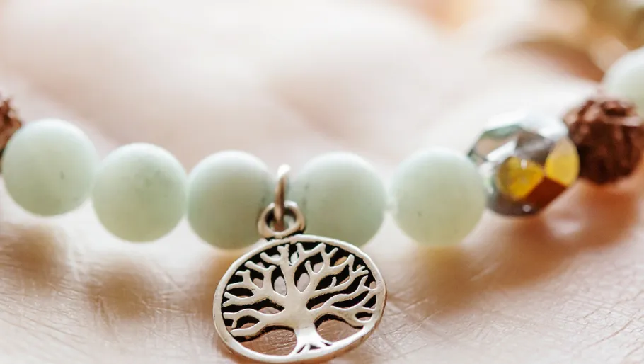 Perlenarmband mit Baumanhänger auf Hand.