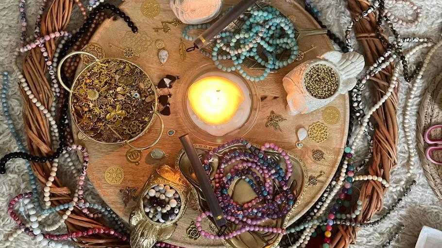 Craft table with beads and a lit candle.