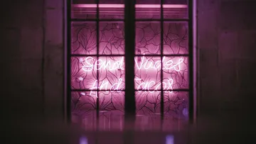 Rosa Neonschild in dunklem Raum.