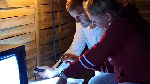 Two people examine papers in dim light.