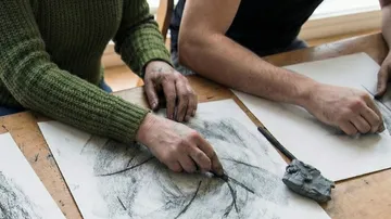 People drawing with charcoal on paper.