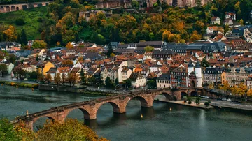 Old bridge over river with colorful town.
