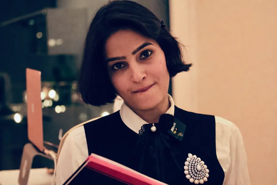 Frau hält Ordner in einem Innenraum, sanft beleuchtet.