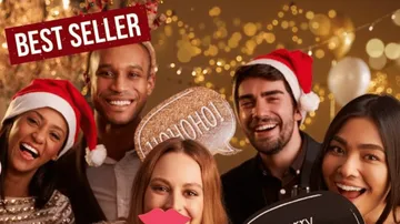Gruppe trägt Weihnachtsmützen und hält Requisiten.