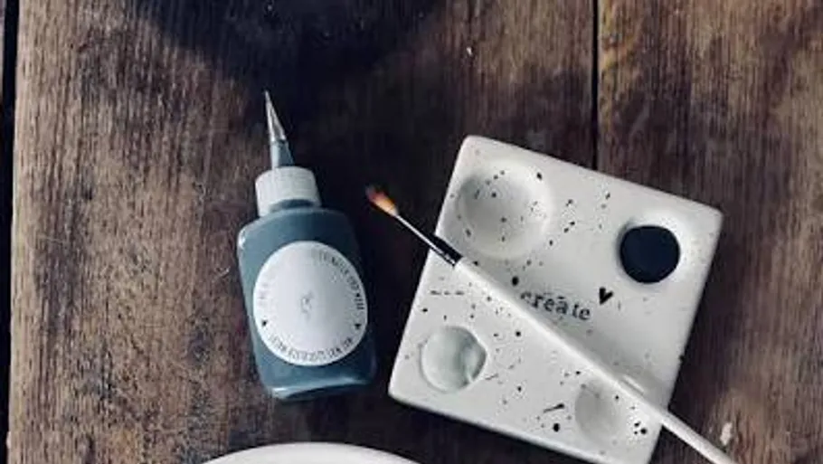 Paint bottle and brush on wooden surface.