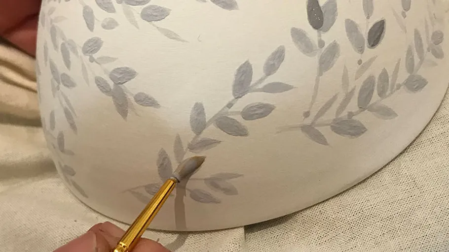 Hand bemalt Blätter auf Keramikoberfläche.