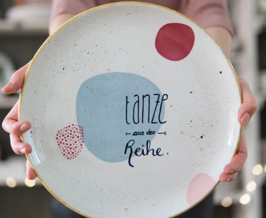 Person holds plate with colorful design.