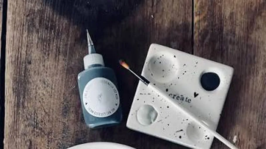 Paint bottle and brush on wooden table.