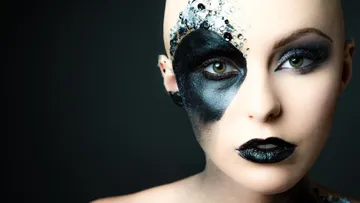 Frau mit künstlerischem Gesichtsmakeup blickt nach vorne.