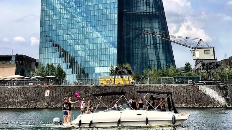 Boat with people near tall glass building.