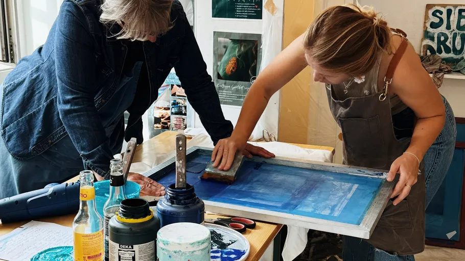Zwei Personen drucken Kunst in Innenräumen.