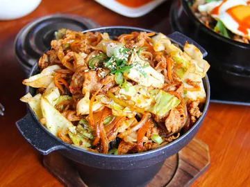 A pot of fried vegetables and meat on a table.