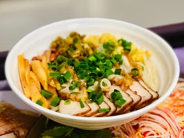 Bowl of rice, vegetables and sliced meat, served.