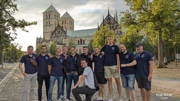 Group of men posing in front of cathedral.