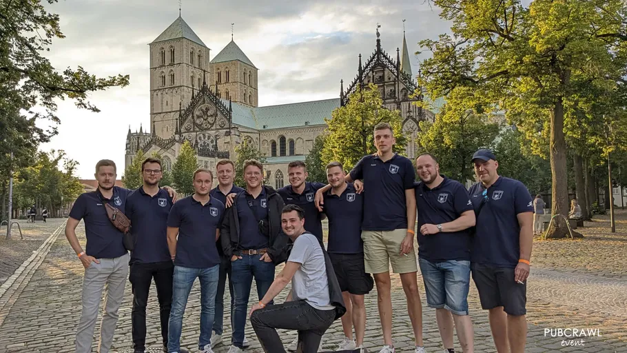 Group of men posing in front of cathedral.