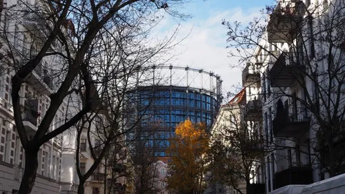 Gasometer umgeben von Gebäuden und Bäumen.