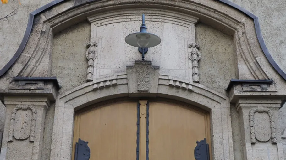 Verzierte Steintür mit Lampe darüber.