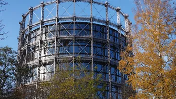 Rundes Gebäude mit Metallrahmen, Herbstbäume.