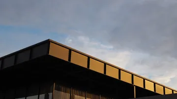 Modern building with golden facade, cloudy sky.