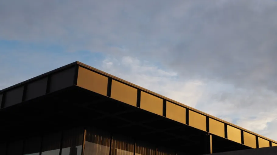 Modernes Gebäude mit goldener Fassade, bewölkter Himmel.