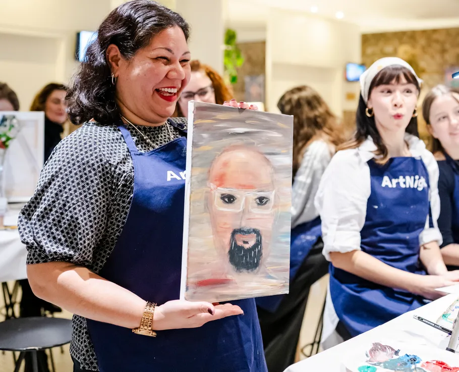 Lächelnde Frau hält Portrait im Malkurs.
