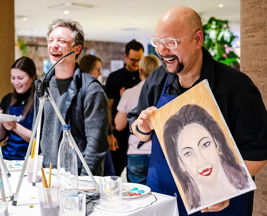 Mann hält Porträtmalerei, lachend, Kunstveranstaltung.