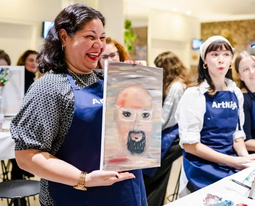 Frau hält Bild bei Kunstveranstaltung.