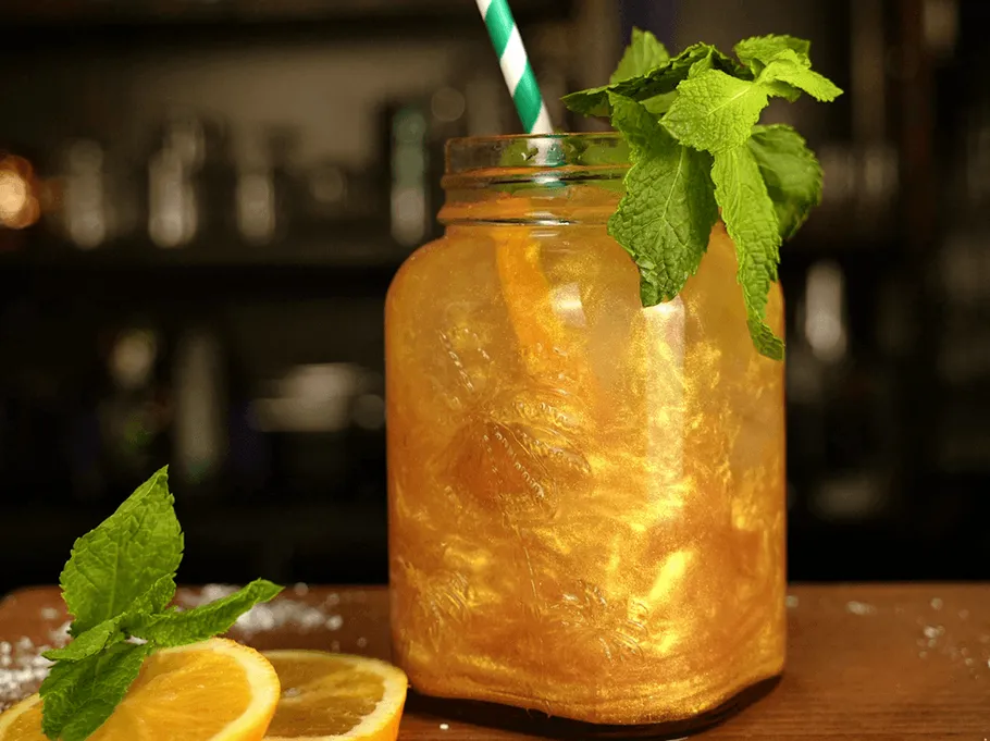 Goldenes Getränk mit Minze im Glas.