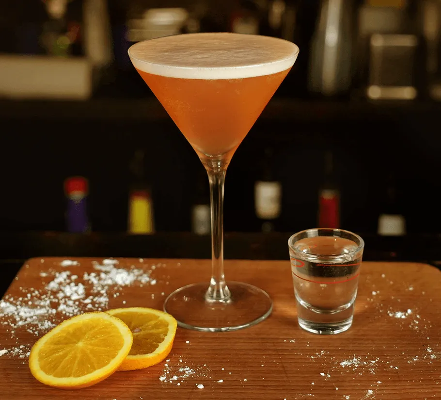 Cocktail and shot glass on wooden surface.