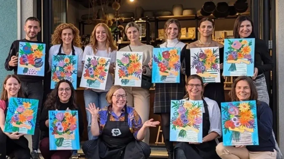 Group holding colorful paintings outdoors.