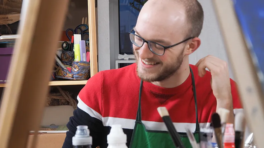 Smiling man painting in art studio.