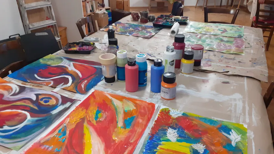 Colorful paintings and paint bottles on table.