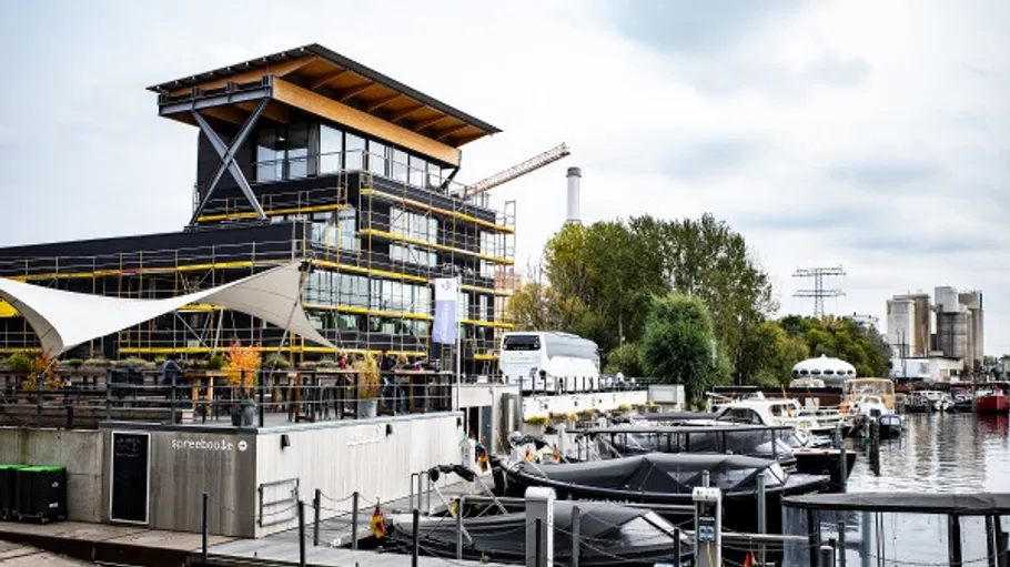 Modern building beside riverside with boats docked.