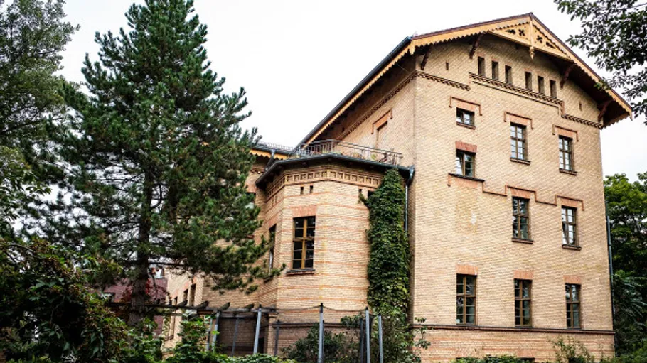 Altes Ziegelgebäude von Bäumen umgeben.