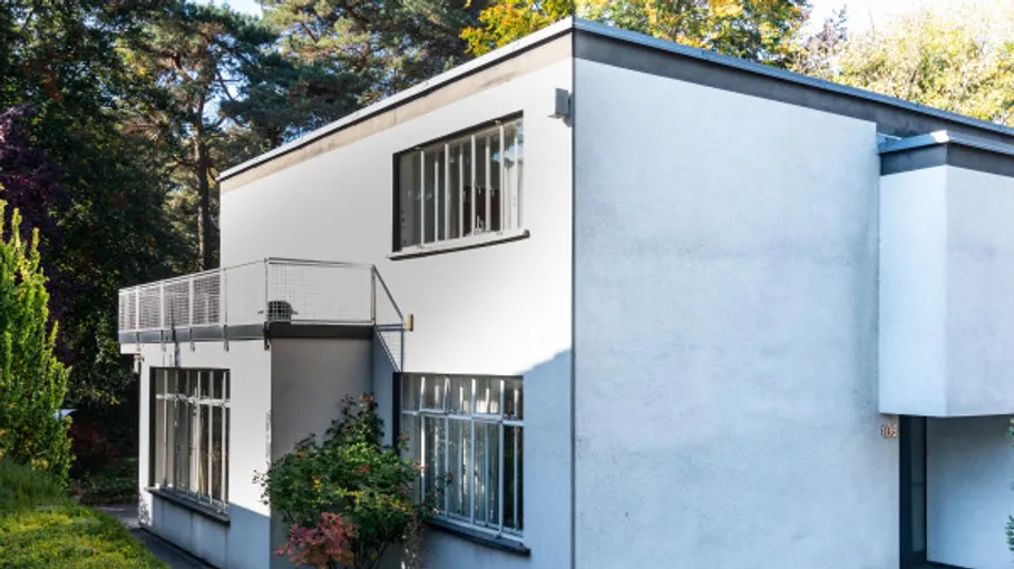 Modern white building with balcony in forest.