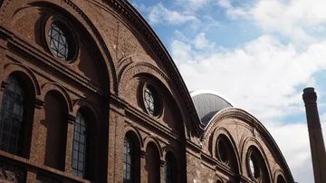 Industrielles Gebäude mit Backsteinbögen, bewölkter Himmel.