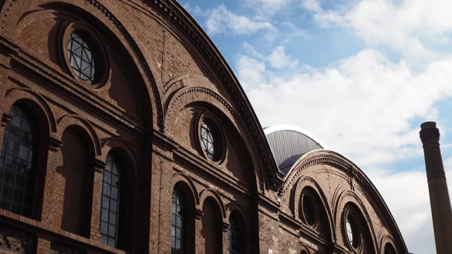 Industrial building with brick arches, cloudy sky.
