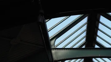 Metallrahmen mit Glasdecke, Himmel sichtbar.