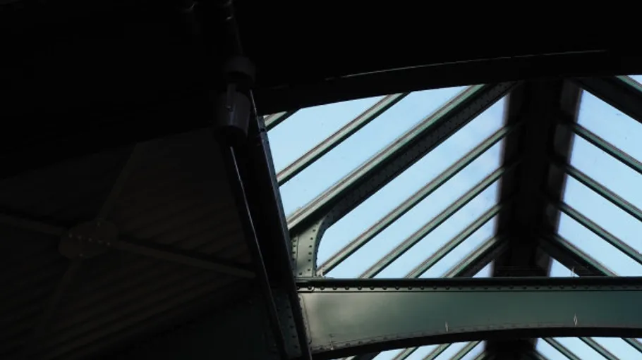 Metal framework with glass ceiling, sky visible.