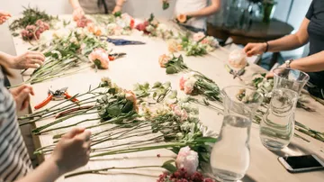 Leute arrangieren Blumen an einem Tisch.