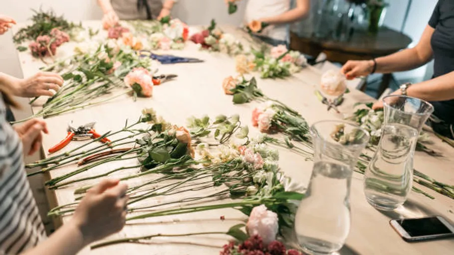 People arranging flowers around a table.
