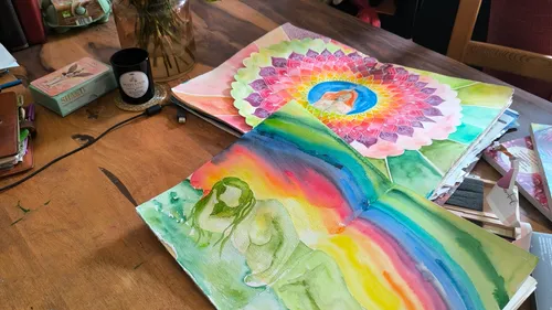 Colorful paintings of woman and mandala on table.