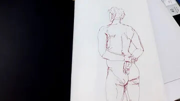 Sketchbook open with a figure drawing inside.