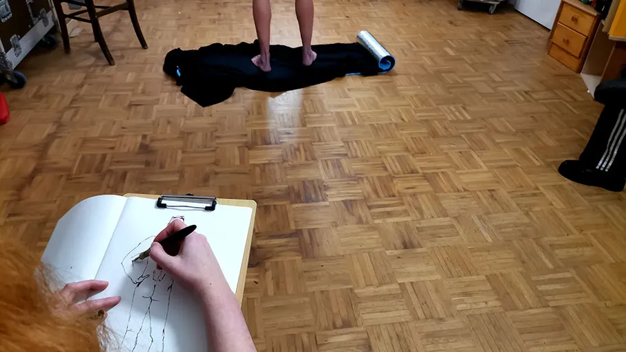 Künstler skizziert Modell auf schwarzem Tuch stehend.