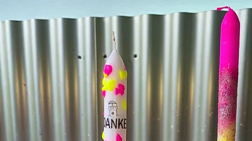 Two decorated candles, corrugated metal background.